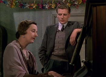 Movie still from “This Happy Breed” (1944), directed by David Lean – An older woman sitting next to a man in a suit; Medium shot, Over the shoulder angle