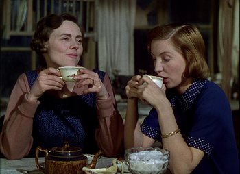 Movie still from “This Happy Breed” (1944), directed by David Lean – Two women are sitting at a table and drinking tea; Medium shot, High angle