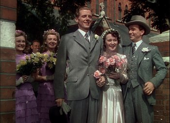 Movie still from “This Happy Breed” (1944), directed by David Lean – A man and a woman are standing together; Medium shot, Low angle