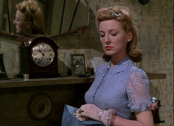 Movie still from “This Happy Breed” (1944), directed by David Lean – A woman in a blue dress is holding a bag; Medium shot, Low angle