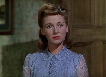 Movie still from “This Happy Breed” (1944), directed by David Lean – A woman in a blue dress with a hair piece; Close Up shot, Low angle