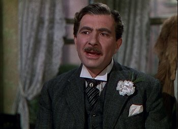 Movie still from “This Happy Breed” (1944), directed by David Lean – A person wearing a suit and tie; Close Up shot, Over the shoulder angle