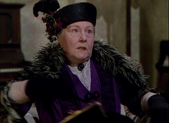 Movie still from “This Happy Breed” (1944), directed by David Lean – An older woman wearing a purple outfit and a black hat; Close Up shot, Over the shoulder angle