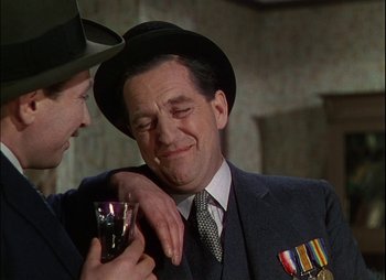 Movie still from “This Happy Breed” (1944), directed by David Lean – A man in a suit and tie holding a glass; Close Up shot, Over the shoulder angle