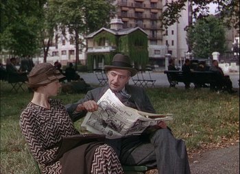 Movie still from “This Happy Breed” (1944), directed by David Lean – An older man and woman sitting on a park bench reading a newspaper; Medium shot, High angle