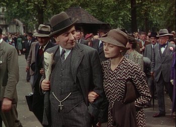 Movie still from “This Happy Breed” (1944), directed by David Lean – An older man and a young woman walking down the street; Medium shot, Low angle