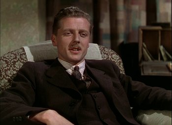 Movie still from “This Happy Breed” (1944), directed by David Lean – A man in a suit and tie sitting in a chair; Close Up shot, Low angle