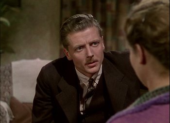 Movie still from “This Happy Breed” (1944), directed by David Lean – A man wearing a suit and tie sitting in front of a woman; Close Up shot, Over the shoulder angle