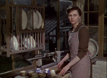 Movie still from “This Happy Breed” (1944), directed by David Lean – A woman standing in front of a rack of plates; Medium shot, Over the shoulder angle