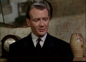 Movie still from “This Happy Breed” (1944), directed by David Lean – A man in a suit and tie in a room; Close Up shot, Over the shoulder angle