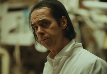 Movie still from “This Much I Know to Be True” (2022), directed by Andrew Dominik – A person with long black hair; Close Up shot, Over the shoulder angle