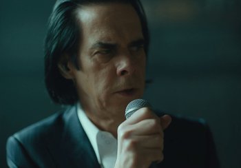 Movie still from “This Much I Know to Be True” (2022), directed by Andrew Dominik – A person holding a microphone; Close Up shot, Low angle