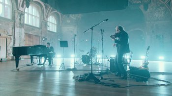 Movie still from “This Much I Know to Be True” (2022), directed by Andrew Dominik – A man in a black suit is playing a microphone; Extreme Wide shot, High angle
