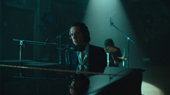 Movie still from “This Much I Know to Be True” (2022), directed by Andrew Dominik – A man sitting at a piano in front of microphones; Medium shot, Over the shoulder angle