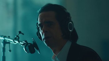 Movie still from “This Much I Know to Be True” (2022), directed by Andrew Dominik – A man wearing headphones and a microphone in front of him; Close Up shot, Low angle
