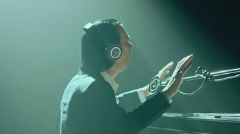 Movie still from “This Much I Know to Be True” (2022), directed by Andrew Dominik – A man wearing headphones and sitting in front of a microphone; Close Up shot, Overhead angle