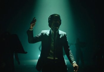 Movie still from “This Much I Know to Be True” (2022), directed by Andrew Dominik – A man in a suit is singing into a microphone; Medium shot, Low angle