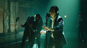 Movie still from “This Much I Know to Be True” (2022), directed by Andrew Dominik – A man in a suit is singing into a microphone; Medium shot, Low angle