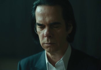 Movie still from “This Much I Know to Be True” (2022), directed by Andrew Dominik – A person wearing a suit and tie; Close Up shot, Low angle