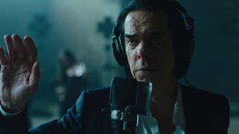 Movie still from “This Much I Know to Be True” (2022), directed by Andrew Dominik – A man with headphones is listening to a microphone; Close Up shot, Low angle