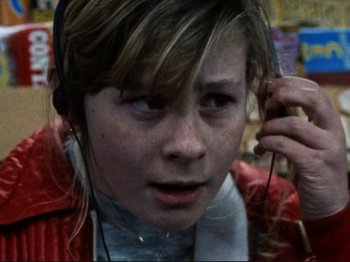 Movie still from “Threads” (1984), directed by Mick Jackson – A young girl is listening to music on her cell phone; Close Up shot, High angle