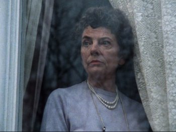 Movie still from “Threads” (1984), directed by Mick Jackson – An older woman looking out of a window at night; Close Up shot, Low angle