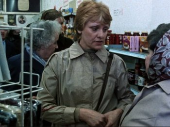 Movie still from “Threads” (1984), directed by Mick Jackson – A woman is standing in a grocery store; Medium shot, Over the shoulder angle