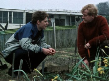 Movie still from “Threads” (1984), directed by Mick Jackson – Two men are talking in a garden together; Medium shot, Over the shoulder angle