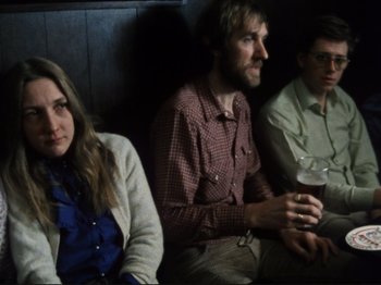 Movie still from “Threads” (1984), directed by Mick Jackson – A group of people sitting next to each other on a couch; Medium shot, High angle