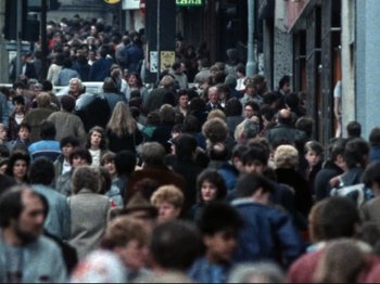 Movie still from “Threads” (1984), directed by Mick Jackson – A crowd of people walking down a street; Extreme Wide shot, High angle