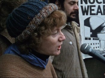 Movie still from “Threads” (1984), directed by Mick Jackson – A woman wearing a hat speaking at a rally; Close Up shot, Over the shoulder angle