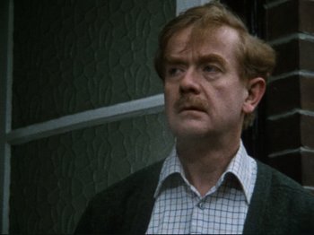 Movie still from “Threads” (1984), directed by Mick Jackson – A person wearing a suit and tie; Close Up shot, Low angle