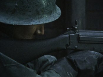 Movie still from “Threads” (1984), directed by Mick Jackson – A man wearing a helmet and holding a rifle; Close Up shot, High angle