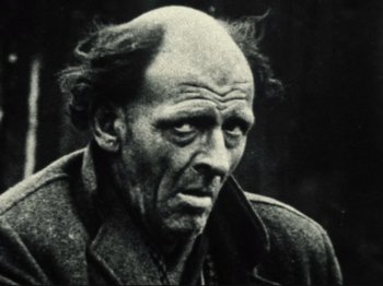 Movie still from “Threads” (1984), directed by Mick Jackson – An old man with a bald head is looking at the camera; Close Up shot, Over the shoulder angle