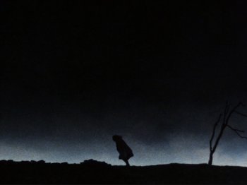Movie still from “Threads” (1984), directed by Mick Jackson – A person walking on a hill at night; Extreme Wide shot, Low angle