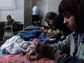 Movie still from “Threads” (1984), directed by Mick Jackson – A group of people sitting around a table knitting; Medium shot, High angle