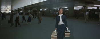 Movie still from “Three Coins in the Fountain” (1954), directed by Jean Negulesco – A woman in a blue suit carrying two suitcases; Wide shot, Low angle
