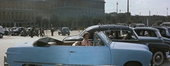Movie still from “Three Coins in the Fountain” (1954), directed by Jean Negulesco – A woman sitting in the passenger seat of a blue car; Wide shot, High angle