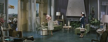 Movie still from “Three Coins in the Fountain” (1954), directed by Jean Negulesco – A woman in a living room cleaning a chair; Wide shot, High angle