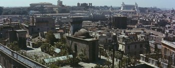 Movie still from “Three Coins in the Fountain” (1954), directed by Jean Negulesco – An aerial view of an urban area with buildings and trees; Extreme Wide shot, High angle