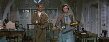 Movie still from “Three Coins in the Fountain” (1954), directed by Jean Negulesco – A man and a woman are walking in a room; Medium shot, Low angle