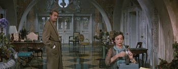 Movie still from “Three Coins in the Fountain” (1954), directed by Jean Negulesco – A man and a woman are standing in a living room; Medium shot, Low angle
