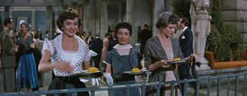 Movie still from “Three Coins in the Fountain” (1954), directed by Jean Negulesco – A group of women standing next to each other holding trays of food; Medium shot, Low angle