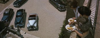 Movie still from “Three Coins in the Fountain” (1954), directed by Jean Negulesco – An aerial view of a car and a car parked in a parking lot; Wide shot, Overhead angle