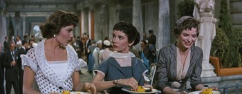Movie still from “Three Coins in the Fountain” (1954), directed by Jean Negulesco – A woman sitting at a table with a plate of food in front of her; Medium shot, Over the shoulder angle