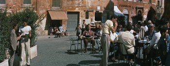 Movie still from “Three Coins in the Fountain” (1954), directed by Jean Negulesco – A group of people sitting on chairs in a courtyard; Wide shot, High angle