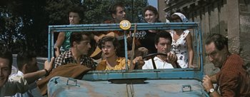 Movie still from “Three Coins in the Fountain” (1954), directed by Jean Negulesco – A group of people sitting in the back of a blue truck; Medium shot, High angle