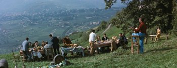 Movie still from “Three Coins in the Fountain” (1954), directed by Jean Negulesco – A group of people sitting around a table on a hill; Extreme Wide shot, High angle