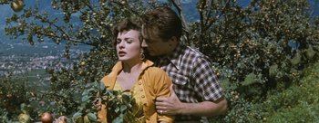 Movie still from “Three Coins in the Fountain” (1954), directed by Jean Negulesco – A man and a woman standing next to each other in front of a tree; Medium shot, High angle
