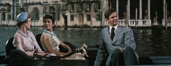 Movie still from “Three Coins in the Fountain” (1954), directed by Jean Negulesco – A man and a woman sitting in a boat in front of a building; Medium shot, High angle